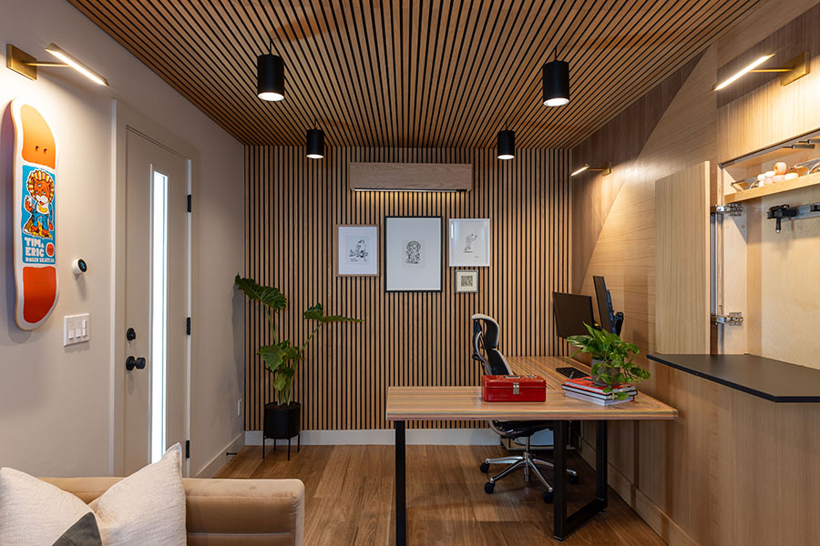 Modern home office with wood paneling, desk, chair, and wall art.