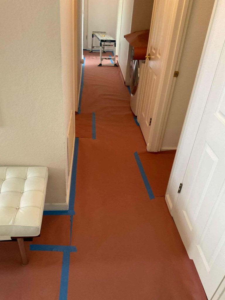 Bellows technicians protect home flooring with red rosin paper and blue tape during heat pump installation in Carmel Valley