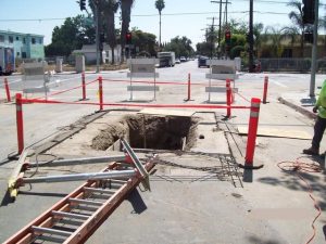 Bellows Plumbing sewer line excavation on a Santa Cruz street with safety cones and road barriers