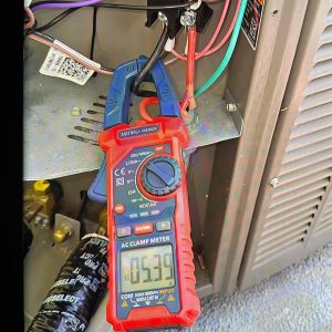 Bellows technician using a clamp meter to check amp draw inside an air conditioner cabinet during an AC repair in Santa Rosa, CA